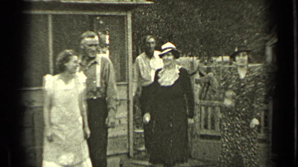 Adults in 1930s clothing stand near a wooden house, fence, and gate in Bend, Oregon home-movie footage.