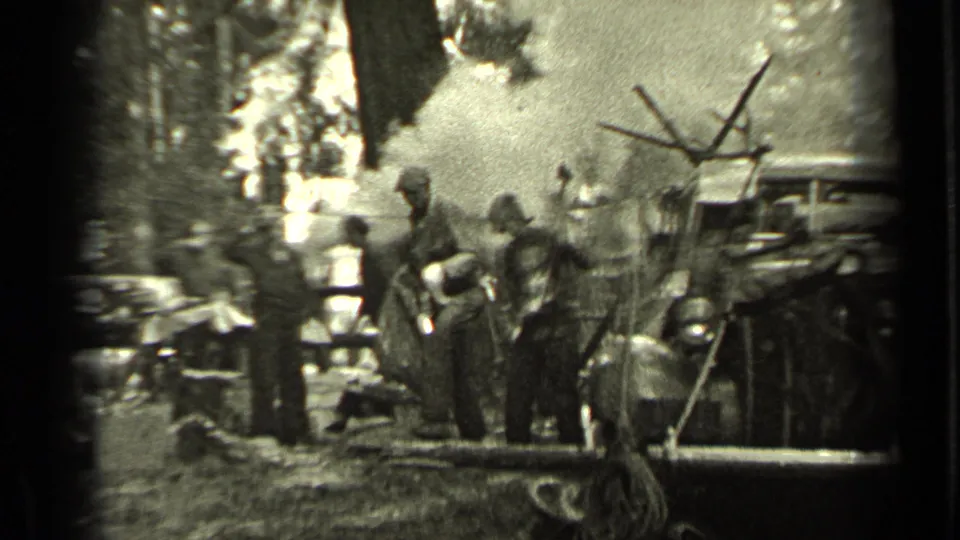 Depression-era Bend, Oregon footage shows men in work clothes near a smoky campsite, trees, equipment, and an older vehicle.