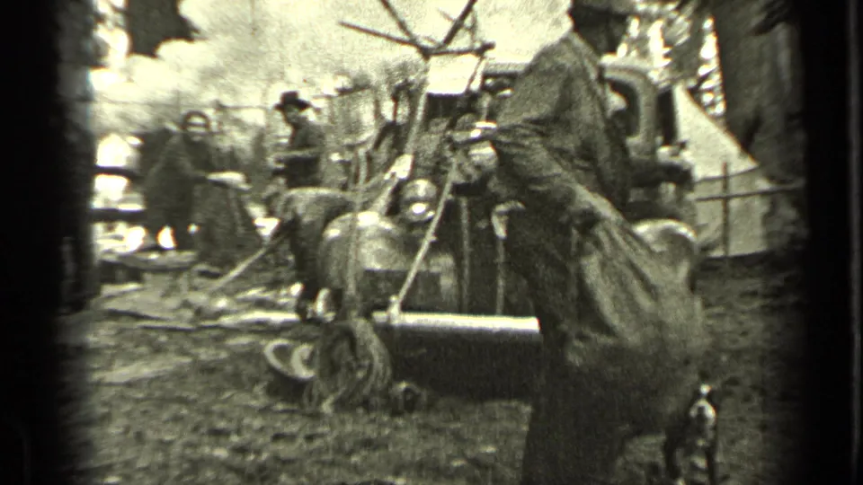 At the end of the Bend, Oregon clip, the sack-carrying man moves away as adults continue working around smoky camp equipment.