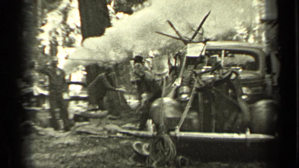 Men in work clothes gather around a smoky campsite near a vintage truck and canvas tent in the supplied 1937 Bend, Oregon home movie.