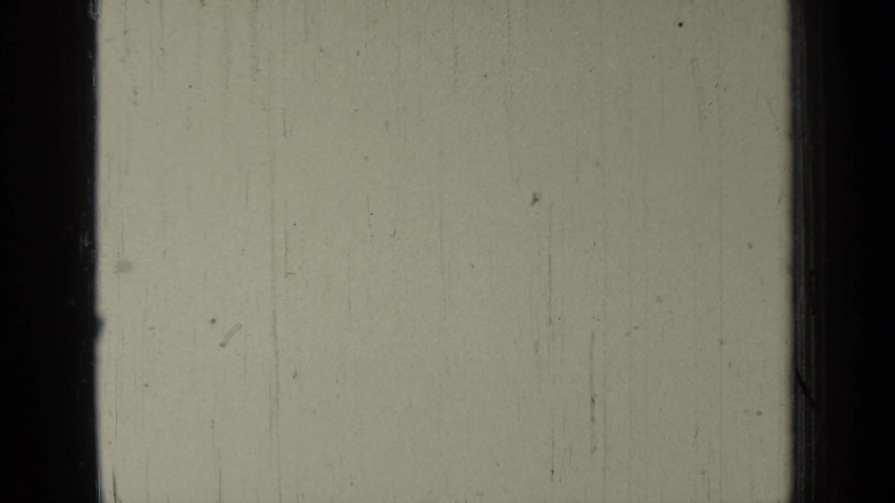 Mostly blank monochrome film frame with dark vertical borders and faint scratches.