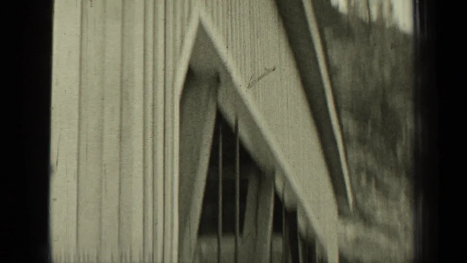 Close, soft-focus 8mm view of wooden covered bridge siding and diagonal support beams during the road crossing.