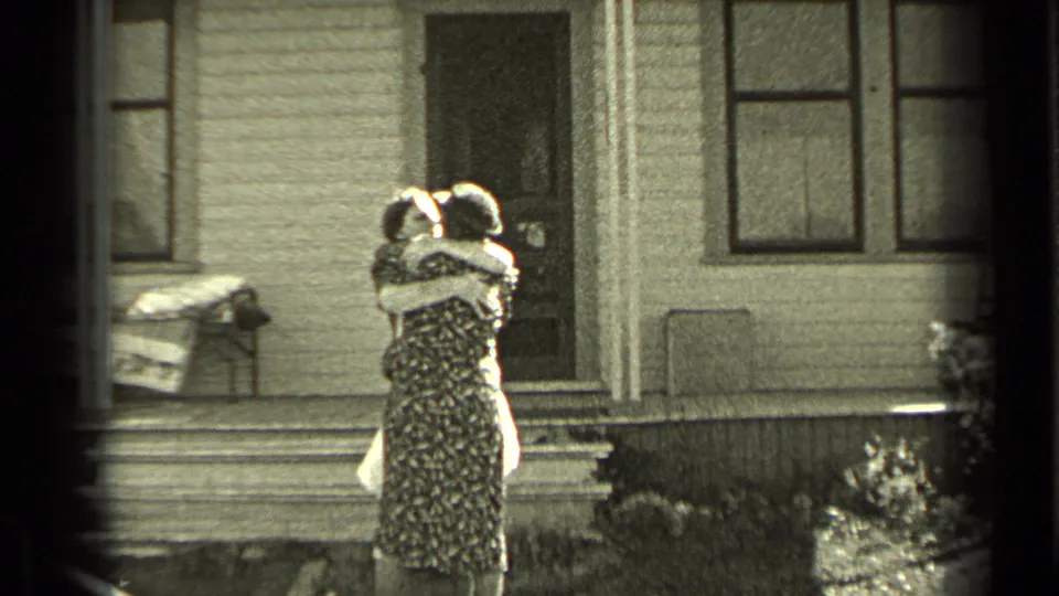 The reunion continues as two women hold an embrace outside the porch of a wood-sided Oregon home.