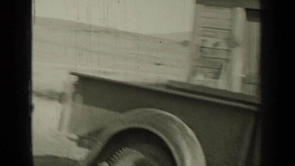 A vintage vehicle stands beside a building in the 1937 Bend, Oregon home-movie scene, partially cropped by the film frame.