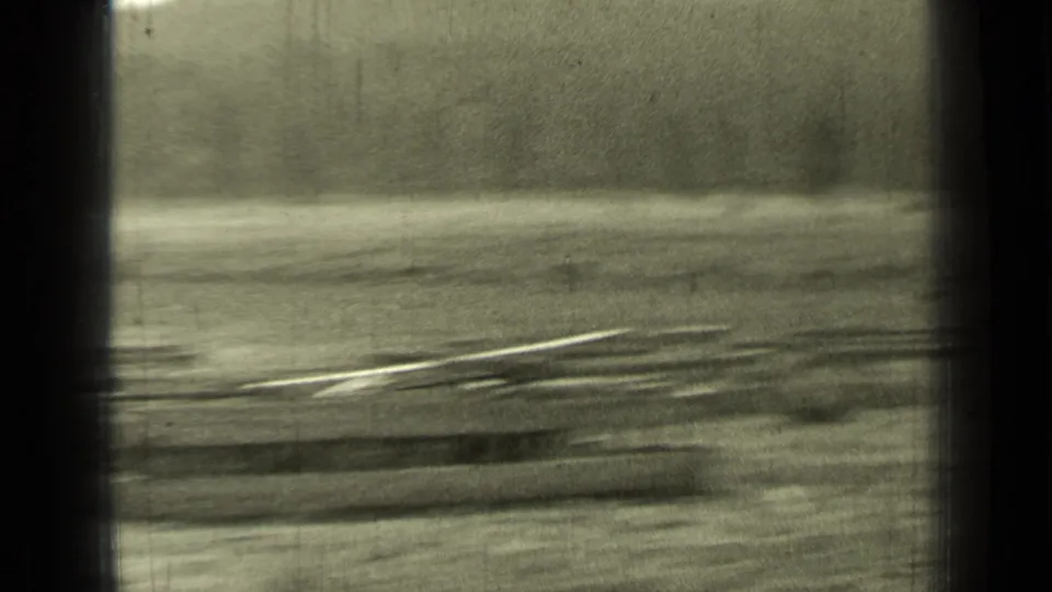 Soft 8mm frame from the Bend, Oregon clip showing open ground, distant brush, and motion blur during a camera move.