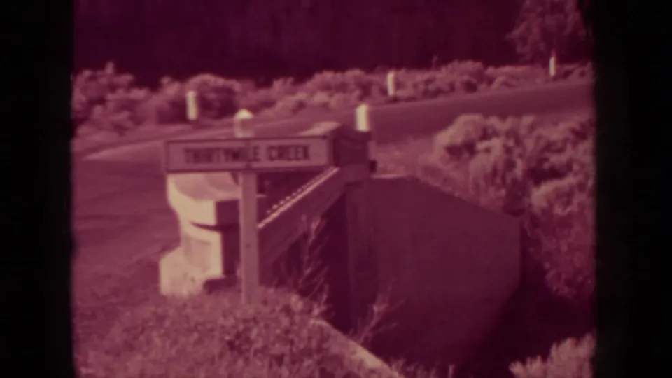 1937 Klamath, California frame with a roadside sign reading Thirtymile Creek, set beside a brushy hillside and road edge.