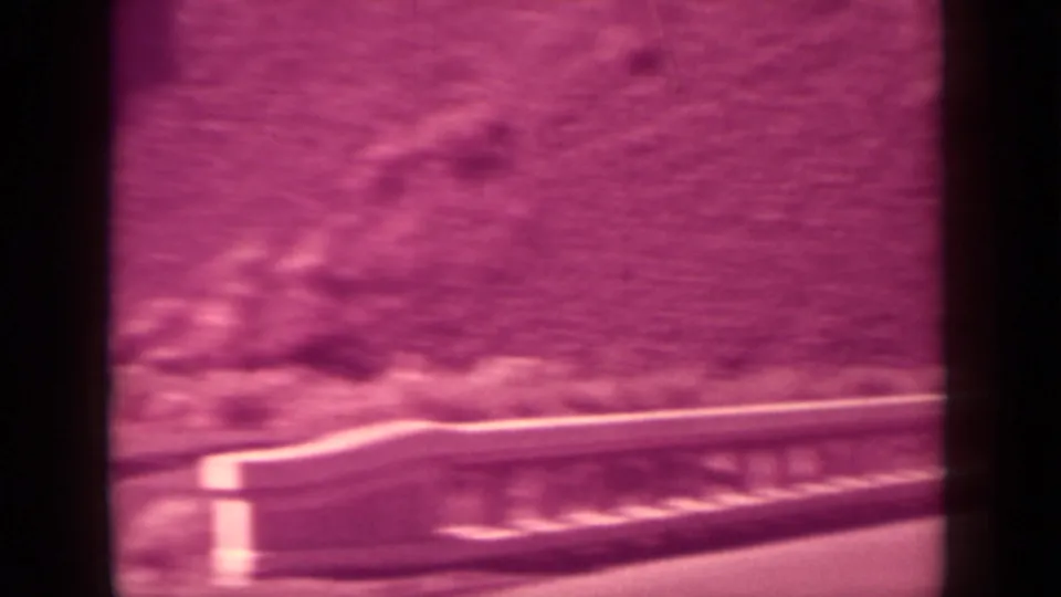 1937 Klamath 8mm frame showing a soft magenta surface, pale horizontal edge, and indistinct dark shapes near the center.