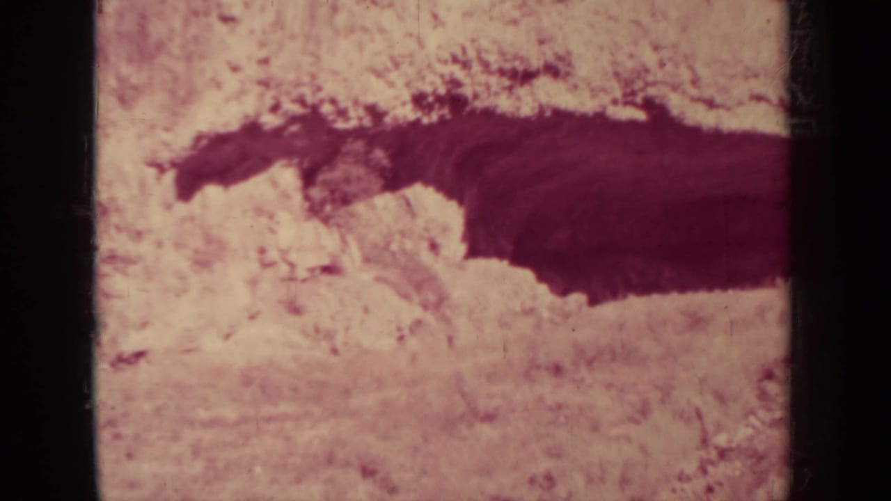Pale desert terrain with a dark canyon-like crevice across the frame.