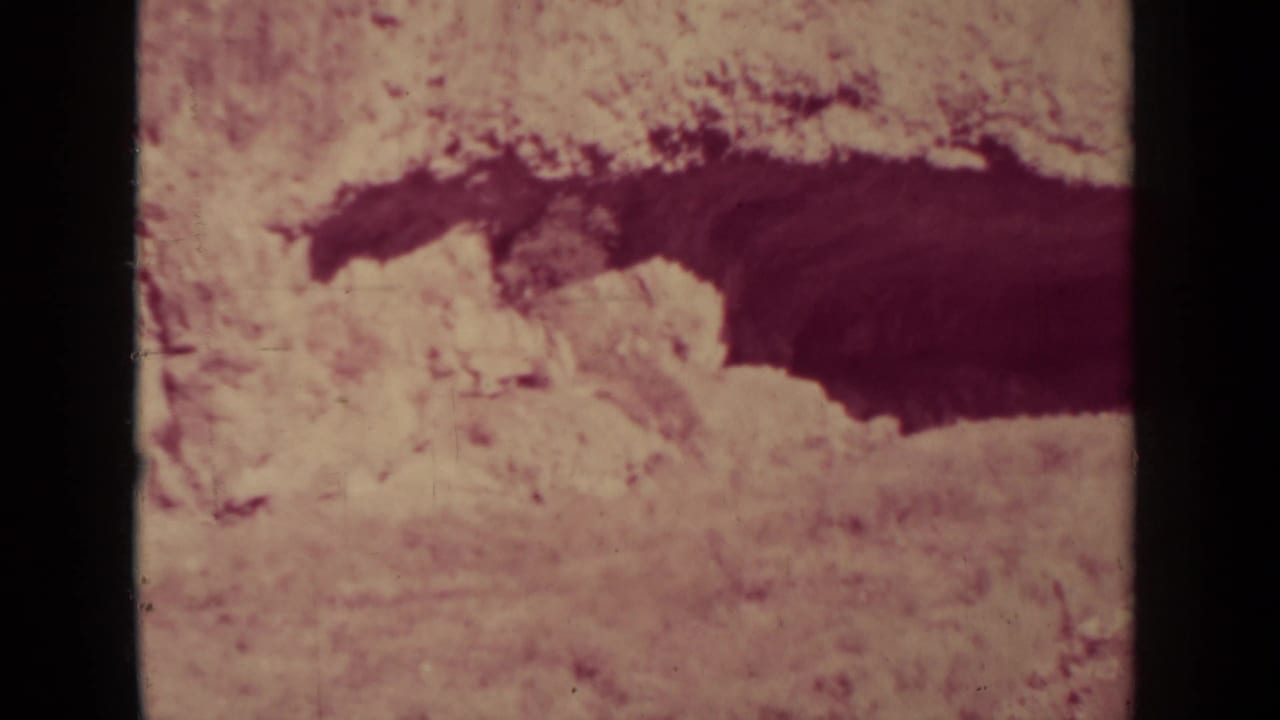 Similar desert view with dark ravine shape and faded film color.