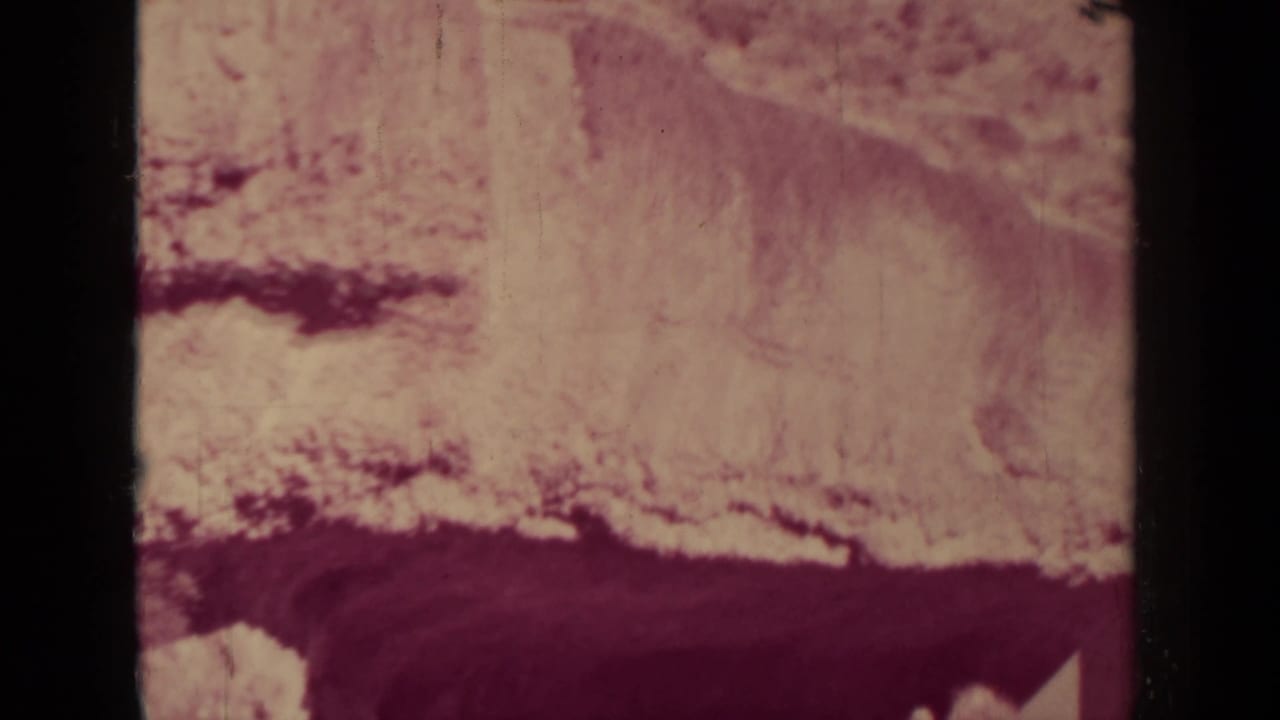 Rock face beside a rail line with dark film borders and reddish tint.