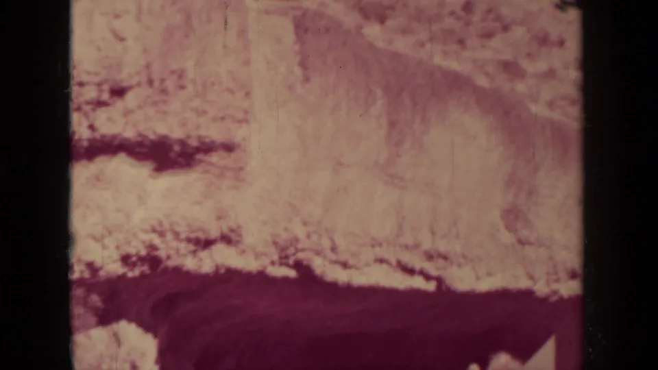 1937 Klamath, California home-movie frame showing a rocky rail-side formation with dark 8mm gate edges and aged color shift.