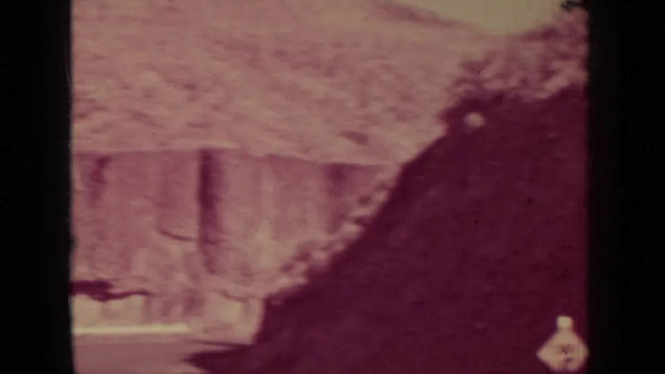 Handheld 8mm view of a large dark rock shape and pale post along the Klamath rail-side setting.