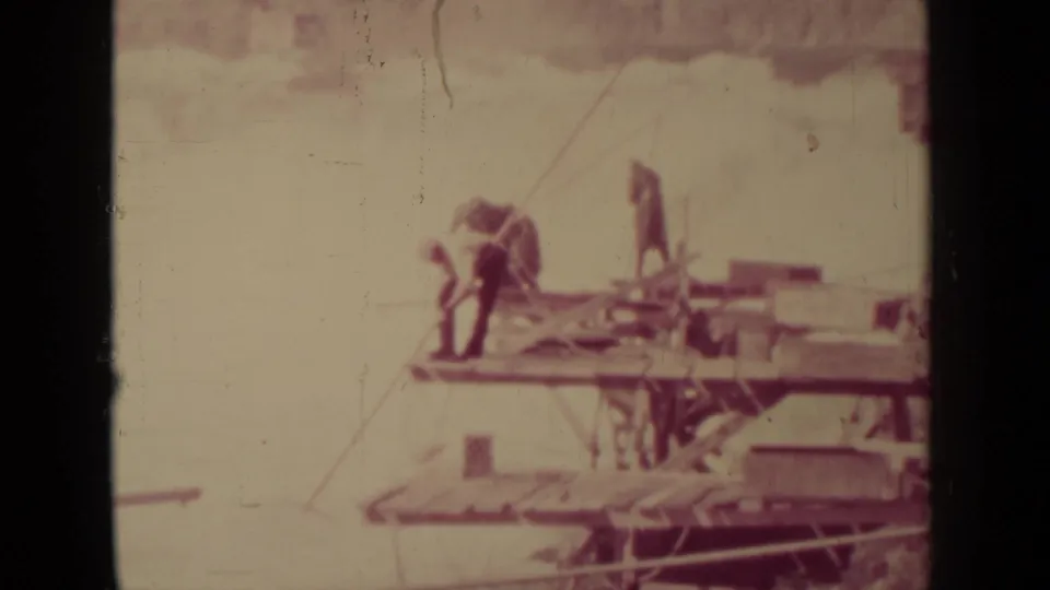 Workers appear on a wooden structure, possibly a dock or bridge, in the same 1937 home-movie travel clip.