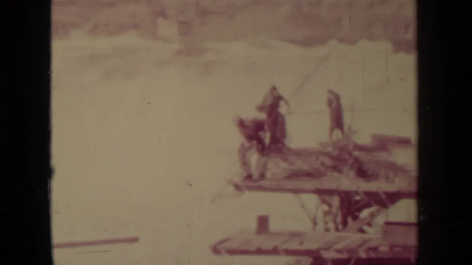 In this 1937 Klamath, California 8mm frame, visitors appear on a wooden overlook beside bright moving water, with heavy scratches and soft focus.