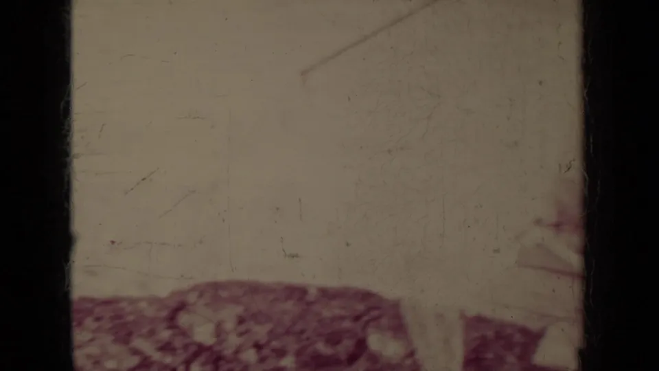 Scratched 8mm frame from the Klamath reel with blank leader-like space, dark frame divider, and a reddish blurred form at the lower right.