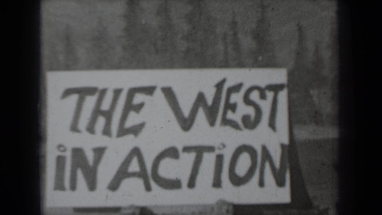 Hand-painted sign reading THE WEST IN ACTION in front of pine trees.