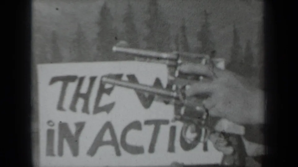 A person’s hand extends two revolvers into frame before the Western sign in the Klamath 1937 home movie.