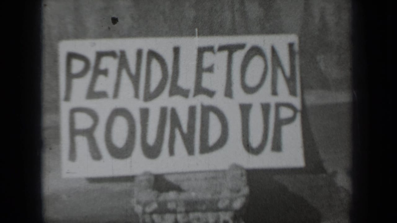 Hand-painted white sign reading PENDLETON ROUND UP held close to the camera.
