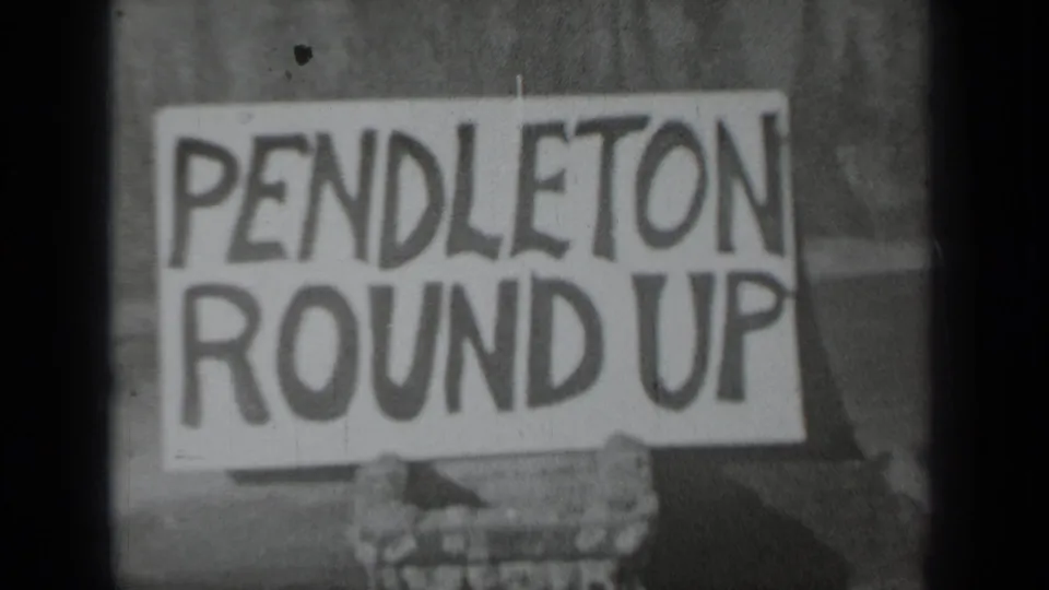 Close 1937 Klamath, California 8mm frame of a white PENDLETON ROUND UP sign with bold lettering and hands at the lower edge.