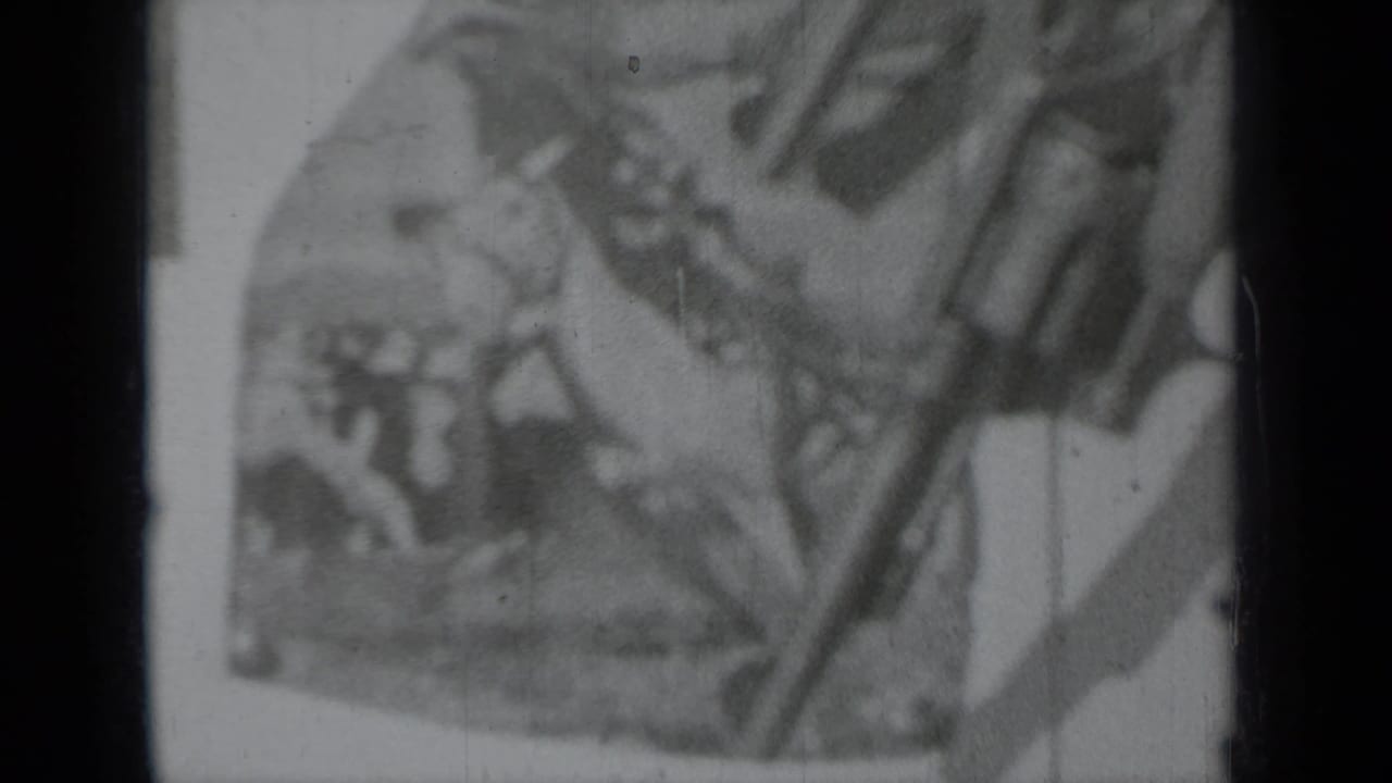 Long gun and hands partly obscuring a horse-and-rider poster.