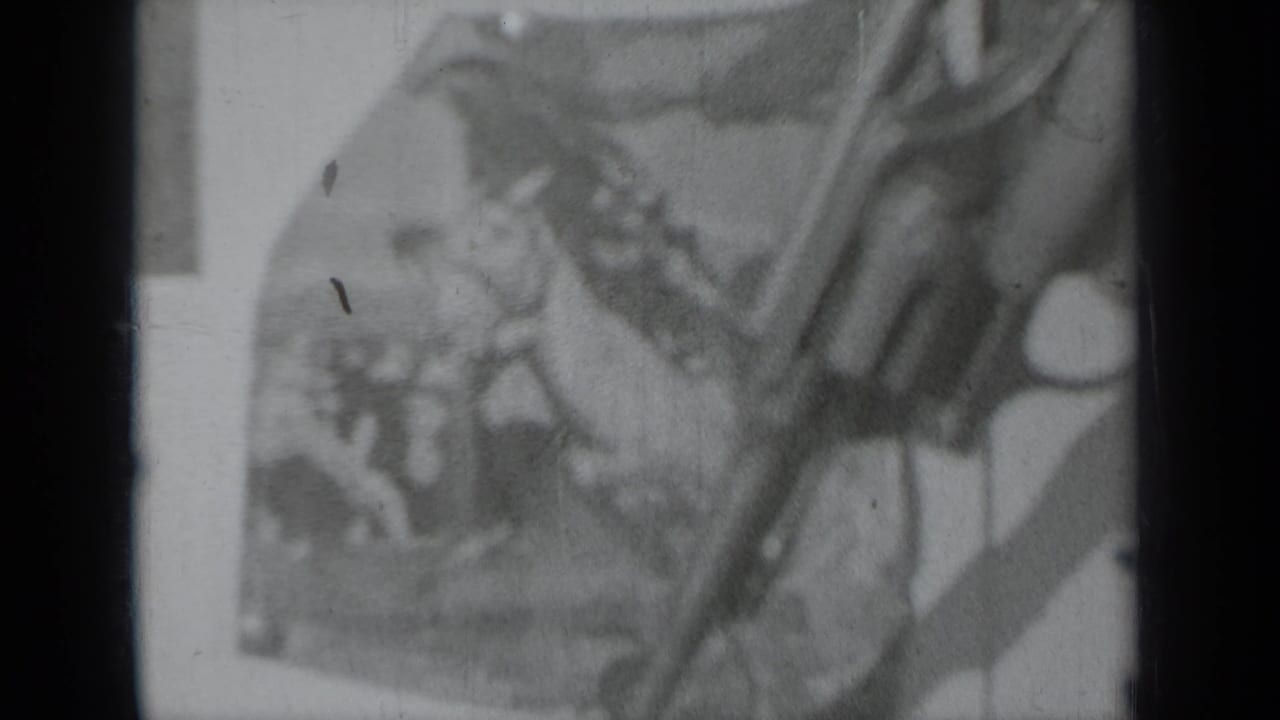 Hands and a long gun in front of a blurred rodeo-style poster.