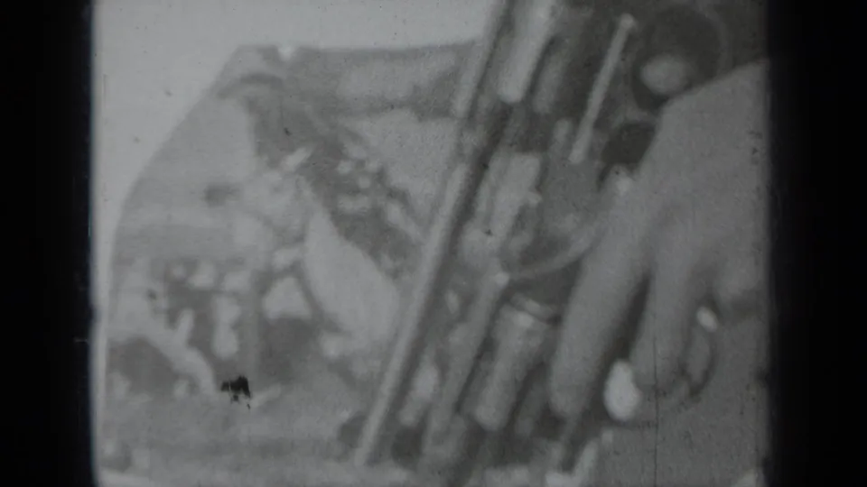 1937 home-movie frame from Klamath, California, showing a close hand-held view of a revolver with soft outdoor background detail.