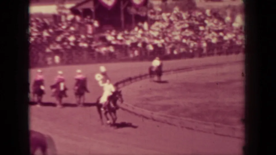 Several riders move around a curved dirt arena in front of crowded bleachers in Klamath, California, 1937.