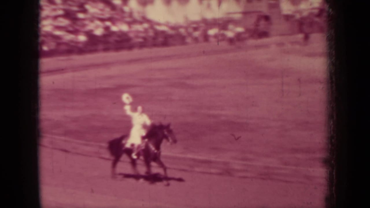 A light-clothed rider on a dark horse crosses the open arena in faded 8mm footage from 1937 Klamath, California.