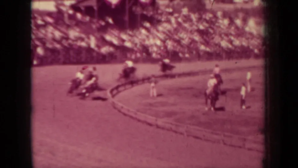 Klamath, California race scene with riders spaced around a dirt oval and a large crowd watching from the stands.