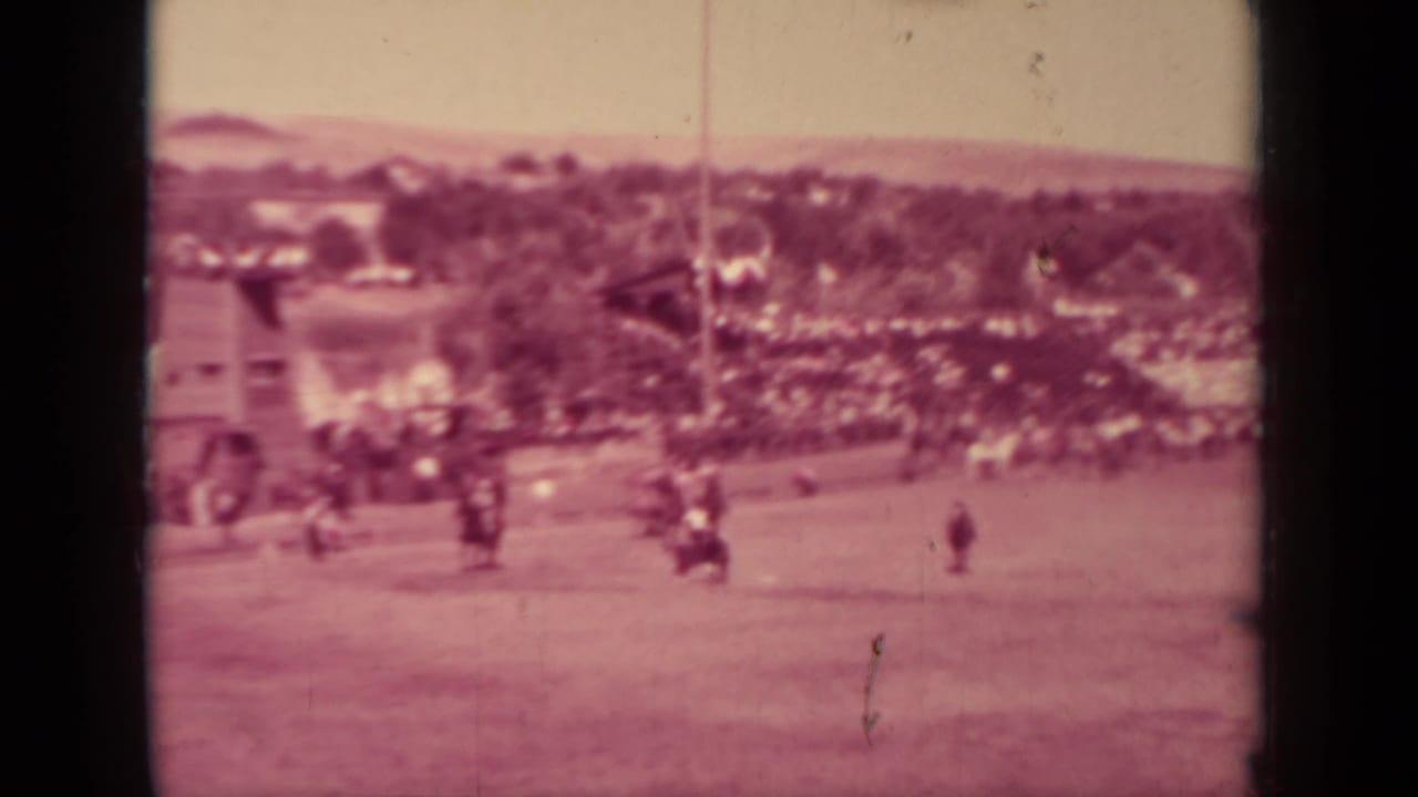 Wide 1937 Klamath, California home-movie view of the racing grounds with spectators, open track, trees, and distant structures.