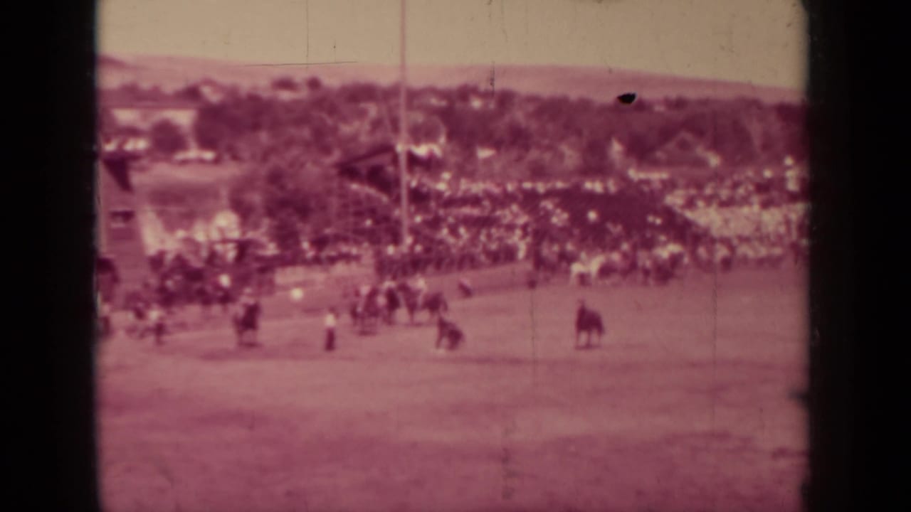 Wide 1937 Klamath, California frame showing the racetrack, distant crowd, riders, trees, and open grounds under faded film color.