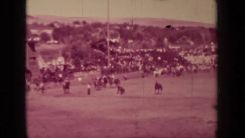 Wide 1937 Klamath, California frame showing the racetrack, distant crowd, riders, trees, and open grounds under faded film color.