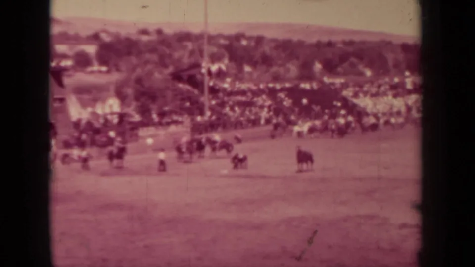 Wide 1937 Klamath, California rodeo view with riders and cattle on a dusty arena field before a crowded rail.