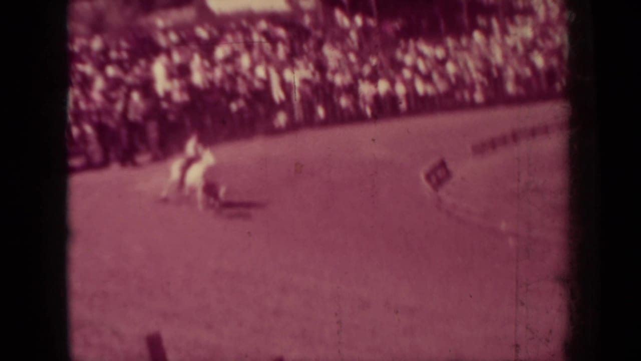 A mounted rider crosses the rodeo arena in front of a crowded rail in the supplied 1937 Klamath, California home-movie footage.