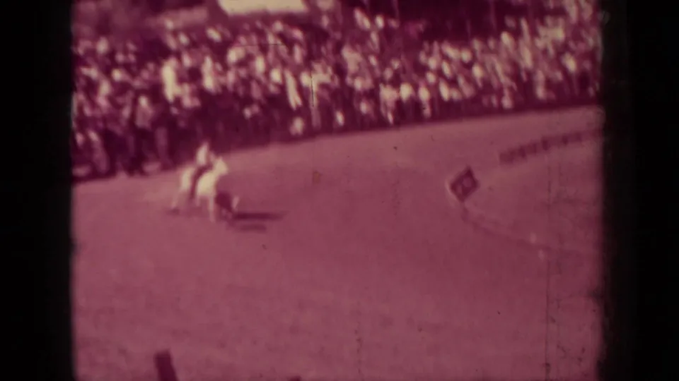 A mounted rider crosses the rodeo arena in front of a crowded rail in the supplied 1937 Klamath, California home-movie footage.