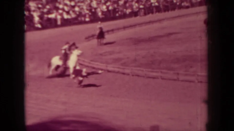 Mounted rodeo riders converge near a calf on the arena ground, with a crowded rail behind them in 1937 Klamath footage.