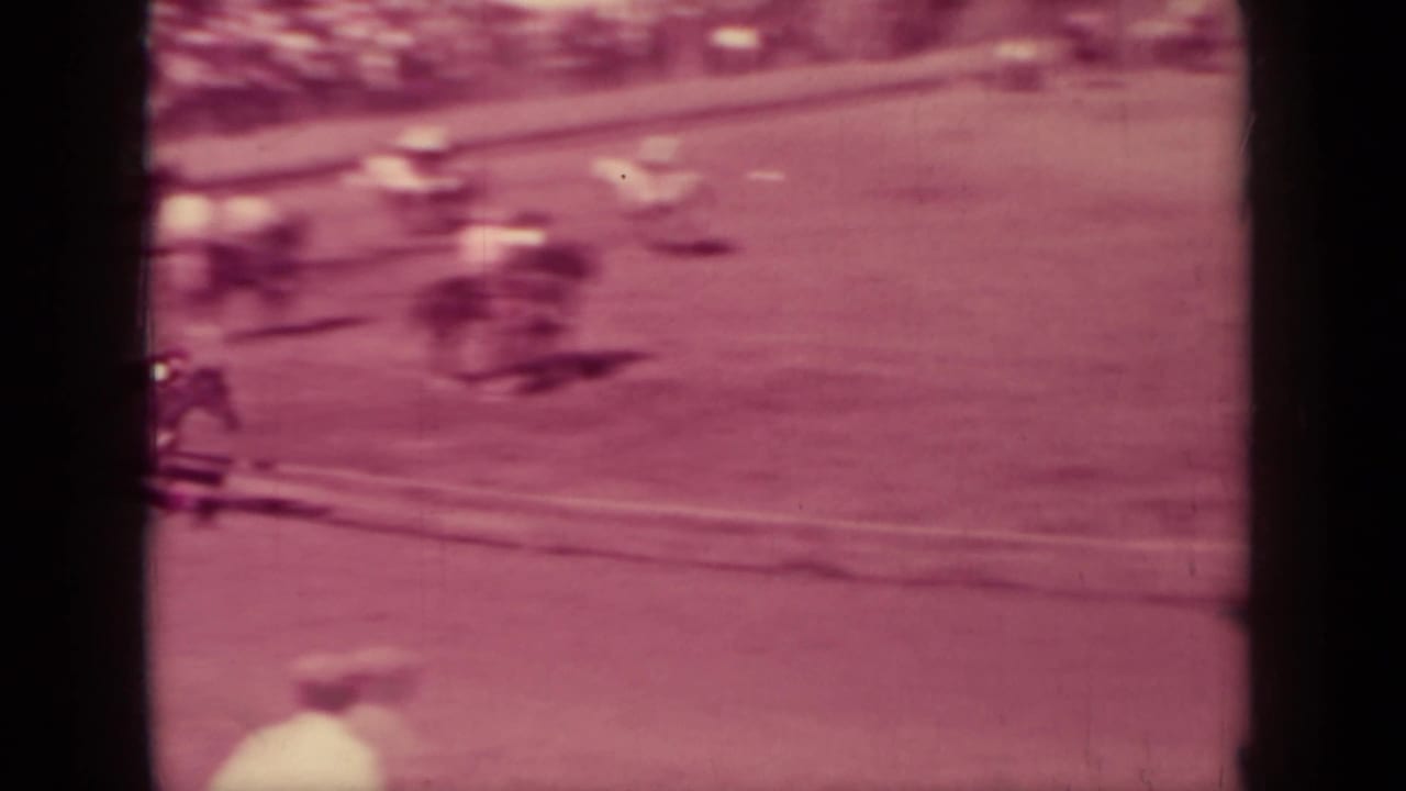 Motion-blurred horses and riders move along the track edge in this magenta-tinted 8mm view from Klamath, California.