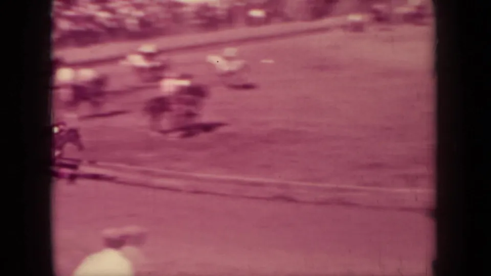Motion-blurred horses and riders move along the track edge in this magenta-tinted 8mm view from Klamath, California.
