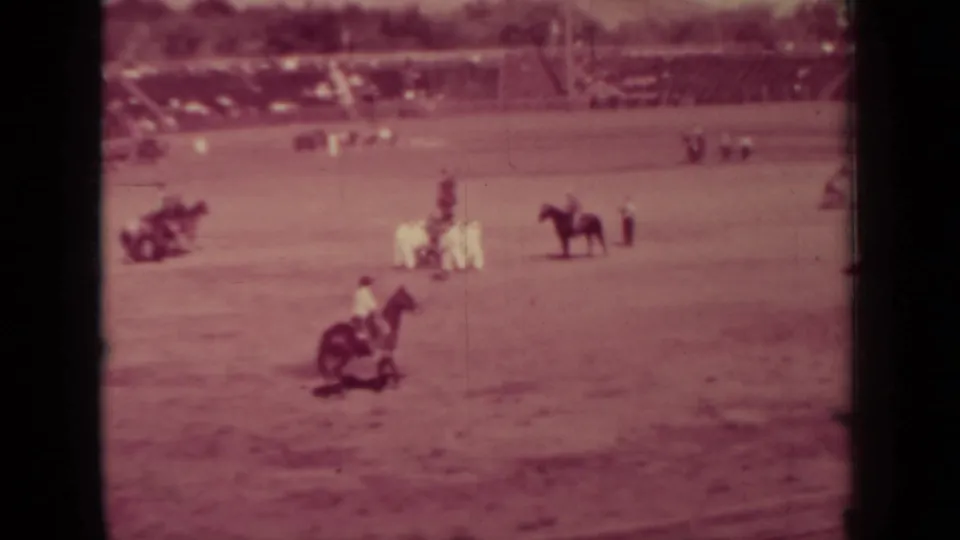 1937 Klamath home-movie still showing a foreground rider, a standing horse, and participants grouped in a dirt equestrian field.