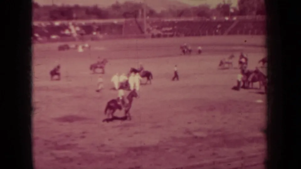 Klamath, California 1937 frame showing multiple mounted riders and participants across a public dirt arena with spectator seating in the background.