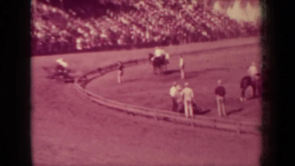 Wide 1937 Klamath, California horse-race frame with attendants on the dirt curve, horses and riders nearby, and spectators filling the stands.