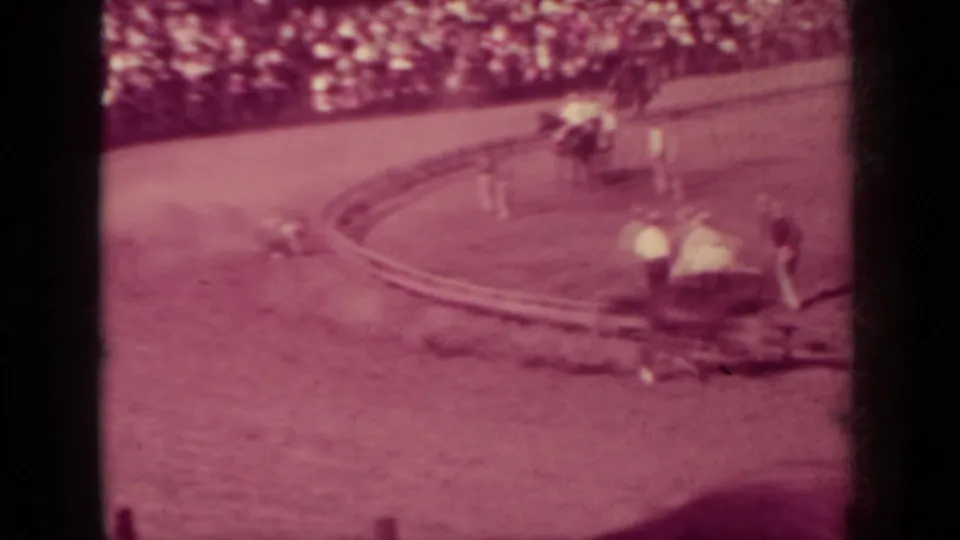 Soft 1937 Klamath, California racetrack view with attendants near the curve, a horse at left, and a crowded grandstand in the background.