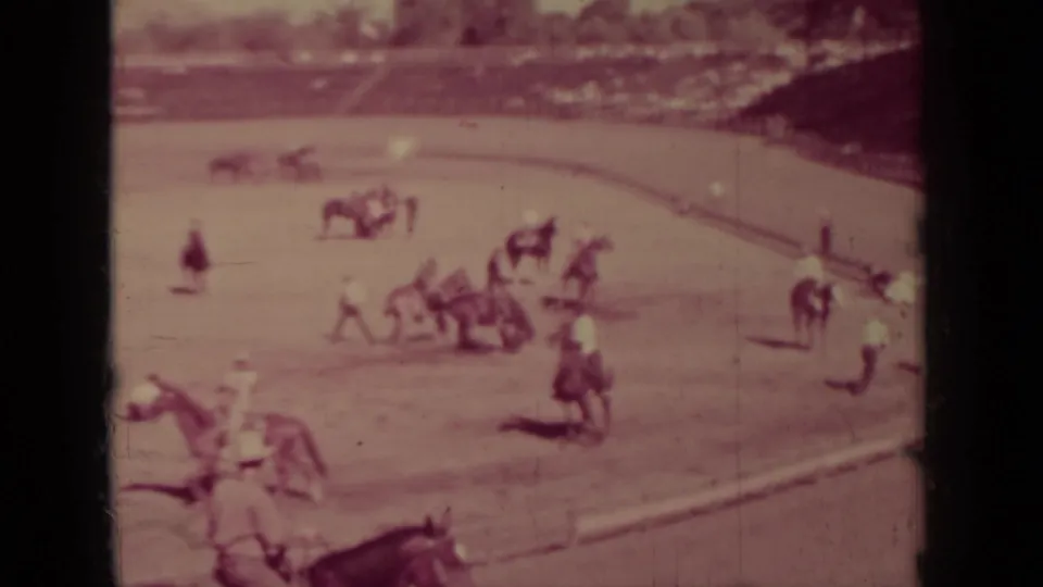 Klamath, California rodeo frame showing riders clustered near the rail while a horse appears to buck in the dusty arena.