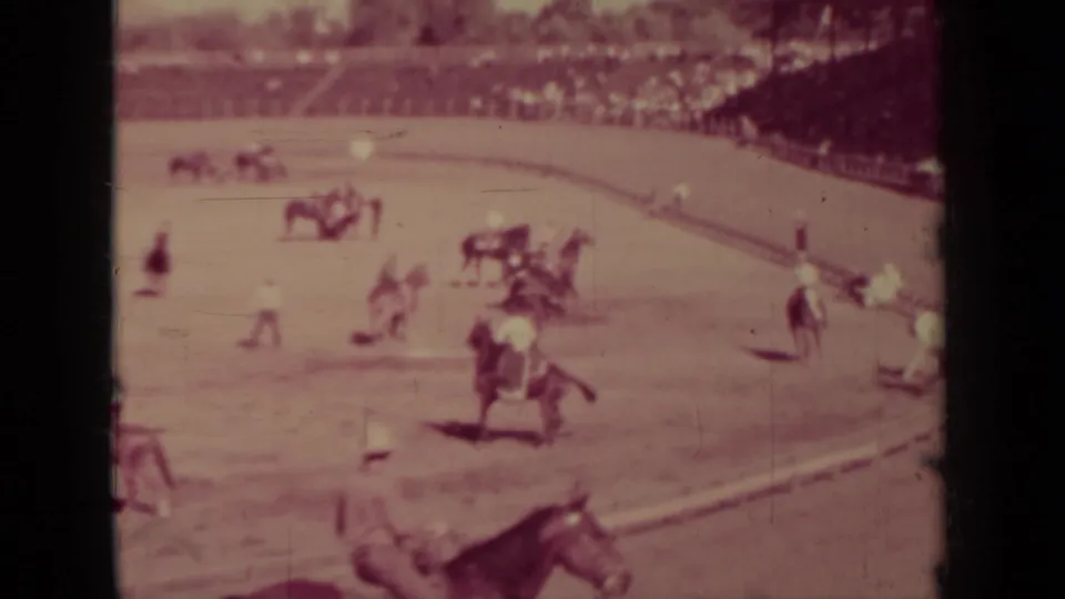 1937 Klamath, California 8mm frame showing several horses and jockeys on a dirt oval before a crowd.