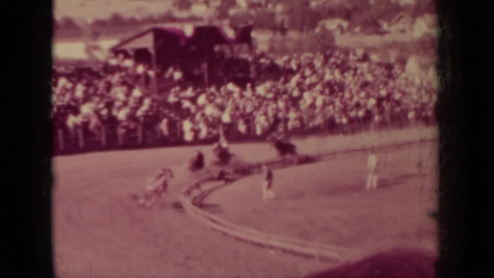 1937 Klamath, California home-movie frame showing a horse and jockey near crowded bleachers at a dirt race track.