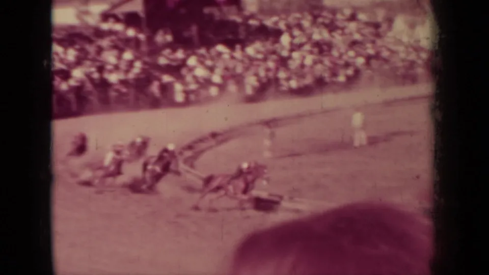 1937 Klamath, California frame showing a cluster of horses and jockeys racing past the crowd on a dirt oval.