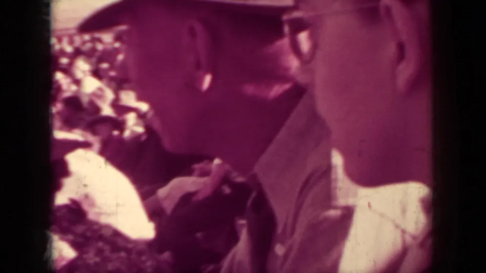 Close 8mm crowd shot at the 1937 Klamath race, showing a man in glasses and other spectators seated closely together.