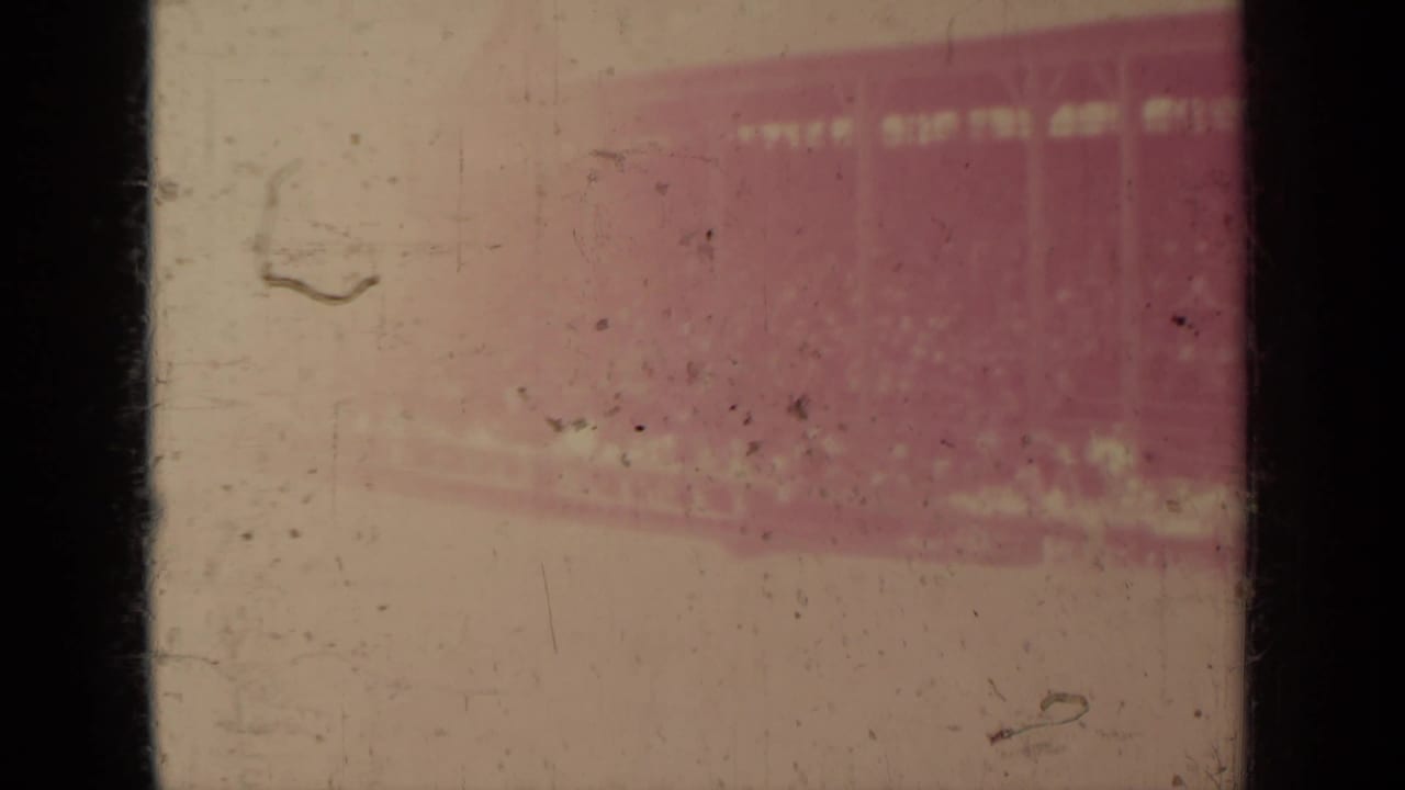 Faded 1937 8mm frame from Klamath footage, showing mostly film leader or overexposed area with scratches and a reddish patch.