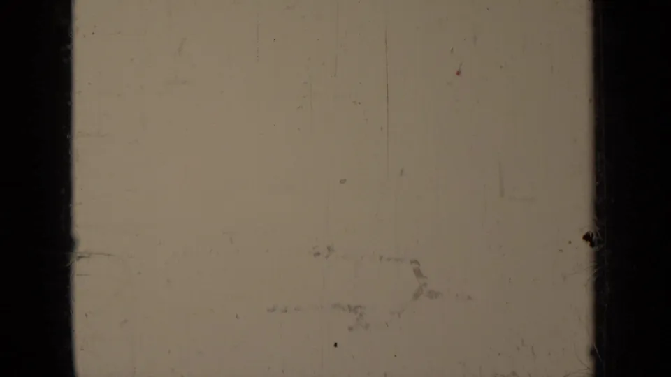 Faded 8mm frame from the Klamath rodeo clip, with little visible action and strong scratches, dust, and dark gate edges.