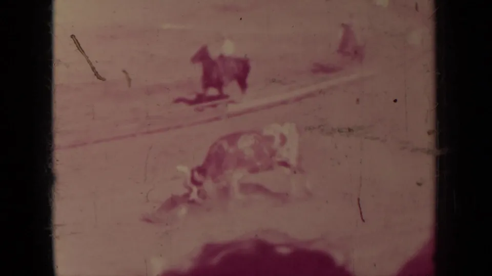 1937 Klamath rodeo frame showing a bull in a dusty arena with small horseback riders in the distance, softened by motion and film fading.